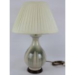 A drip glazed pottery table lamp on turned wood base and with pleated cream shade. Base height 42cm.