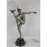 An Art Deco style silvered figural lamp of a nude dancer mounted on a composite marble base.