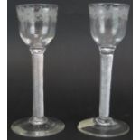 A matched pair of 18th century air twist drinking glasses with floral engraved bowls, plain stems