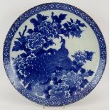 A large antique decorative Japanese porcelain charger with blue and white peacock decoration.