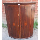 A George III mahogany bow fronted corner cupboard, with crossbanded inlay, housing four fitted
