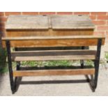 A Victorian/Edwardian beech double school desk, with two rising lids, on cast iron frame.