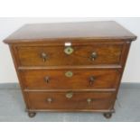 A 17th century oak chest of small proportions, having three long drawers with brass drop handles and