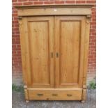 An antique stripped pine double wardrobe, the panelled doors flanked by reeded columns, with one