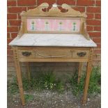 An Edwardian stripped pine marble topped washstand, with tiled back and shaped cornice, housing