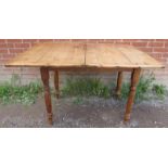 An antique pine turnover kitchen table, with single frieze drawer, on tapering turned supports.