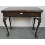 An antique Georgian design mahogany folding card table, with extending back legs, on acanthus carved