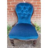 A Victorian mahogany spoonback nursing chair, upholstered in a blue buttoned material, on tapering
