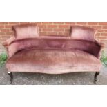 An Edwardian mahogany two-seater sofa, with individual scrolled backrests, upholstered in faded