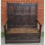 A 19th century high back oak settle in a 17th century taste, featuring relief carved back panels