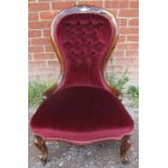 A Victorian mahogany spoonback nursing chair, upholstered in a claret buttoned material, on scrolled