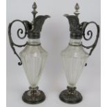 A pair of late 19th century cut and etched glass claret jugs with pewter mounts and silver plated