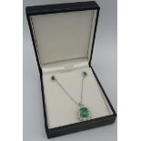 An 18ct white gold emerald & diamond cluster pendant on an 18ct white gold chain with two