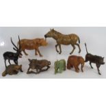 Seven hand carved animal figures including wart hogs, zebra, water buffalo, impala, racoon and