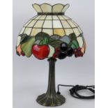 A contemporary Tiffany style table lamp with fruit themed stained glass shade and bronzed leaf style