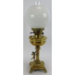 A period brass oil lamp of classical reeded column form with cherub support and opaline glass shade.