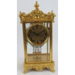 An ornate gilt 8 day striking mantle clock with mercury style pendulum and glazed case. Height 35cm.
