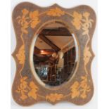 An Edwardian pokerwork framed mirror with flowering vine design surrounding a bevelled oval mirror.