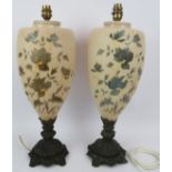 A pair of 1920s French glass lamps decorated with blue floral enamel design and standing on cast