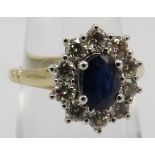 A 9ct yellow and white gold sapphire and diamond cluster ring, size M/N. Oval-cut sapphire approx