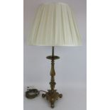 A vintage heavy brass tripod candlestick lamp with two bulb fitting and associated pleated cream