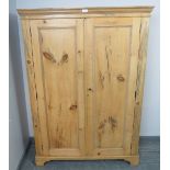 An antique stripped pine pantry cupboard, the double doors opening onto fitted shelves, on bracket