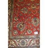 Persian Tabriz carpet central flowered pattern on red ground, with a deep border predominantly in