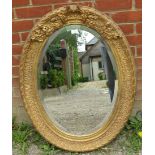 A 19th century French style bevelled oval wall mirror in an ornate gilt gesso frame. Condition