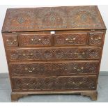 An 18th century oak bureau, featuring extensive relief carving, the fall front opening onto a fitted