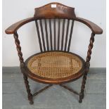 An Arts & Crafts oak oval elbow chair, with bergere seat and barley twist uprights united by a