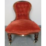 A Victorian mahogany spoonback nursing chair, upholstered in red velvet buttoned material, on
