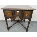A 19th century oak lowboy in a 17th century taste, housing three short drawers with cast brass
