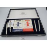 A boxed Bridge set, comprising of four silver biros with enamelled red and black card symbols,