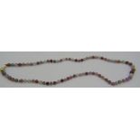 A multi coloured tourmaline bead necklace with small interspersed yellow metal beads on a 14ct