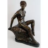 A contemporary bronze figure of a reclining male nude perched on a rock, mounted on a black marble