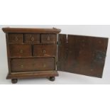 A 17th/18th century oak spice cabinet containing six graduated drawers and with inlaid door with