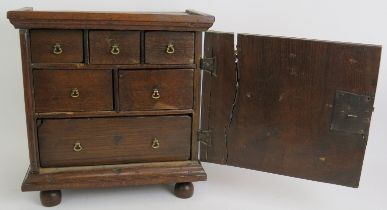 A 17th/18th century oak spice cabinet containing six graduated drawers and with inlaid door with