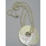 A fresh water pearl necklace with a mother of pearl circular pendant, on a silver ball clasp, boxed.