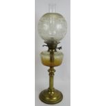 An antique brass based oil lamp with slice cut glass reservoir double wick burner and etched glass