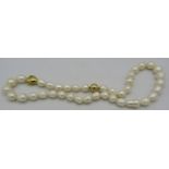 A white baroque pearl necklace with heart shaped yellow metal bead and 18ct yellow gold ball clasp