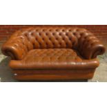 A vintage 2 seater Chesterfield style sofa upholstered in deep buttoned chestnut leather with