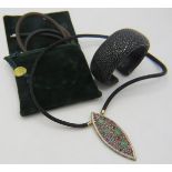 A black shark skin necklet with a large white metal pendant set with many precious & semi precious