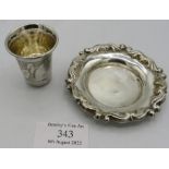 A small white metal dish with applied edge, eastern marks and a small silver tot measure with leaf