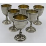 A set of six Russian white metal Vodka cups with gilded interior bowls and maker's mark to base.