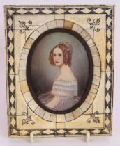 A 19th century continental portrait miniature of a lady in a decorative bone frame. Indistinctly