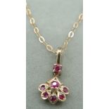 A child's yellow metal pendant set with a fan shape of six amethysts with one other amethyst on