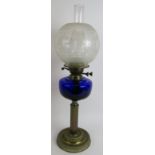 An antique brass oil lamp with Gadrooned base, blue glass reservoir and etched shade. Overall height