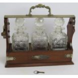 An antique oak three decanter tantalus with silver plated mounts by Richard Richardson. Full working