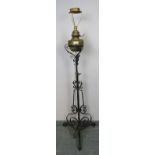 A Victorian wrought iron and brass standard lamp, on ornately scrolled base. Has been converted from