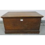 A small antique oak flat top trunk, with brass handles to either side, on a plinth base. Condition